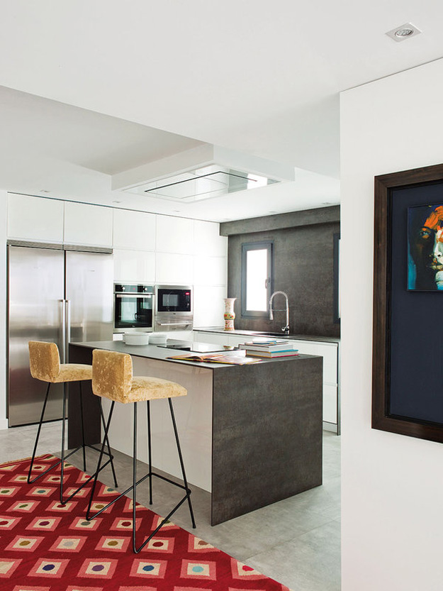 The kitchen is rather small, kept in white and grey - stainless steel appliances and concrete cooking surfaces