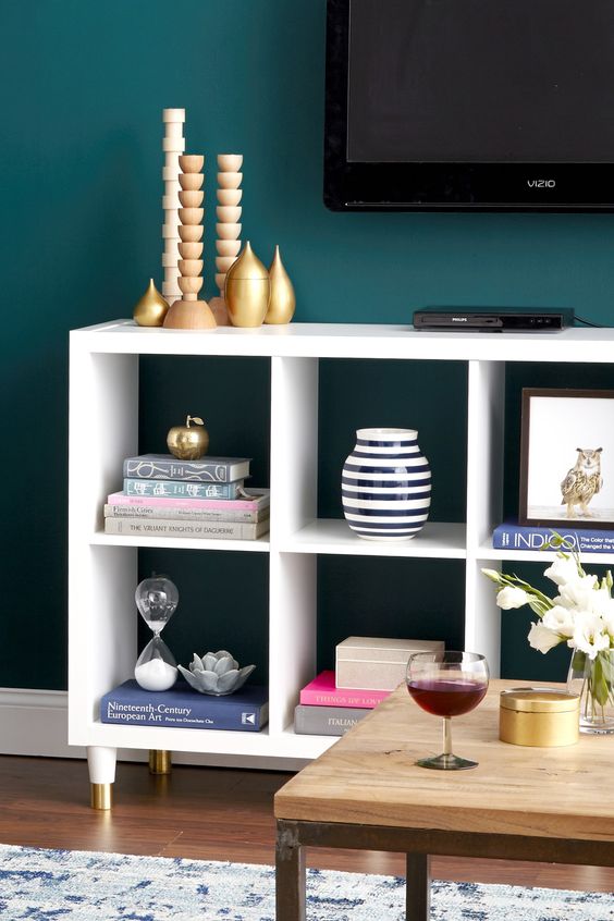 an Ikea Kallax shelf as a stylish and elegant TV unit, with gold legs and some gold decor on the shelf is a lovely idea