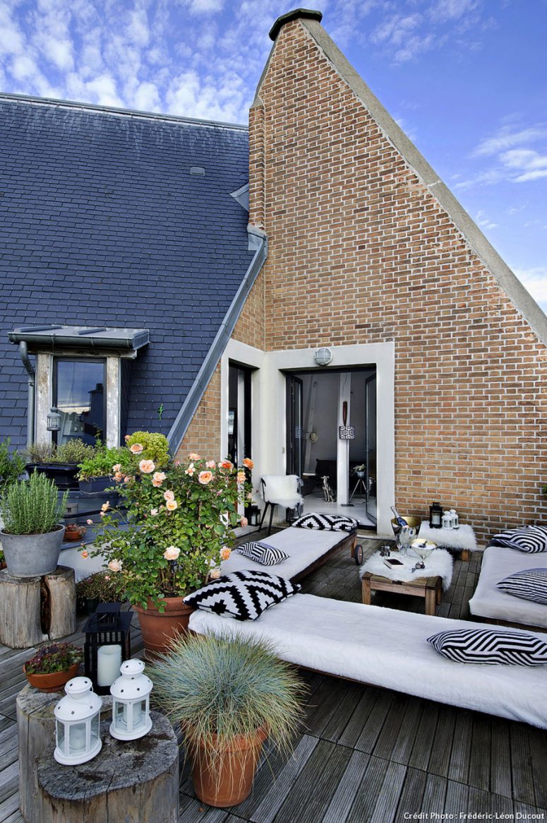 The terrace with a weathered wooden deck continues the interior decor in black and white