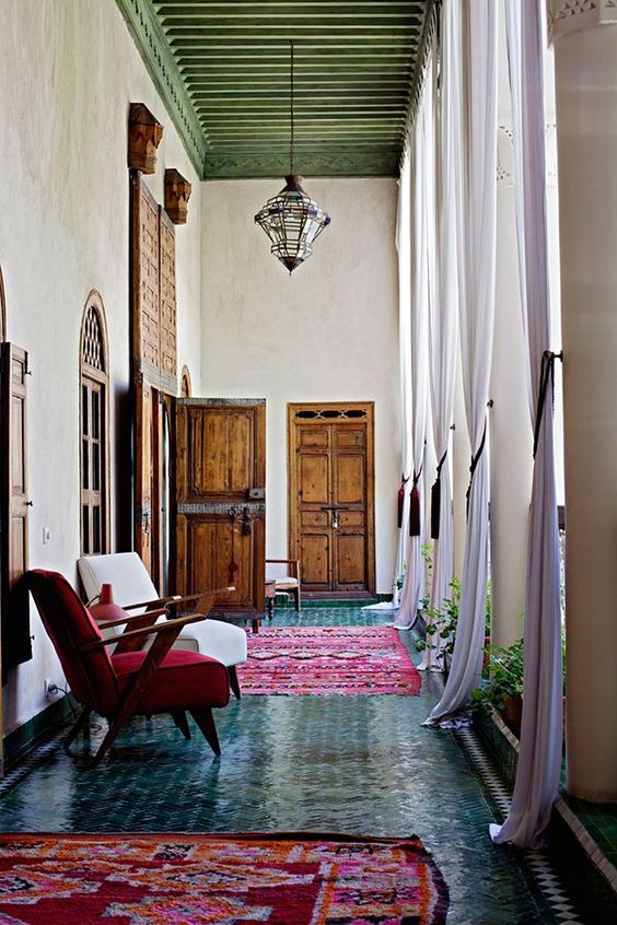 Moroccan hallway with green tiled floor and red rugs and chairs