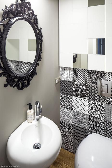 The toilet is decorated with differently printed tiles and a vintage mirror