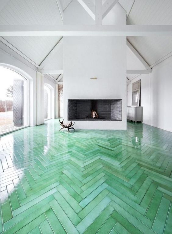 green herringbone wooden floors are a bold decoration feature in this white room