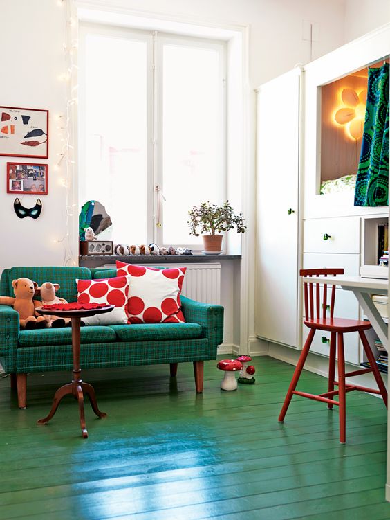 Green painted floors and couch with red pillows