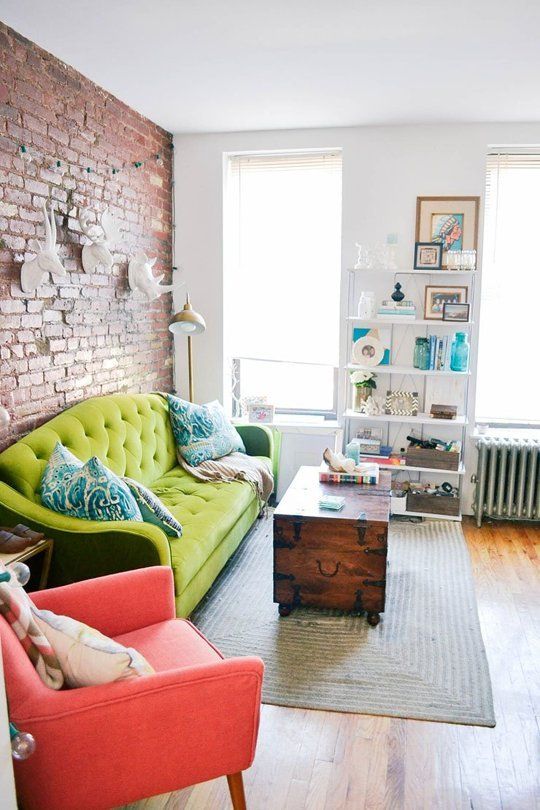 Neutral living room with a bold green sofa and red chair that stand out