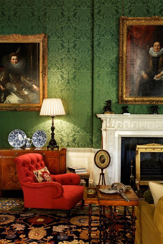 Green damask walls and a red tufted chair