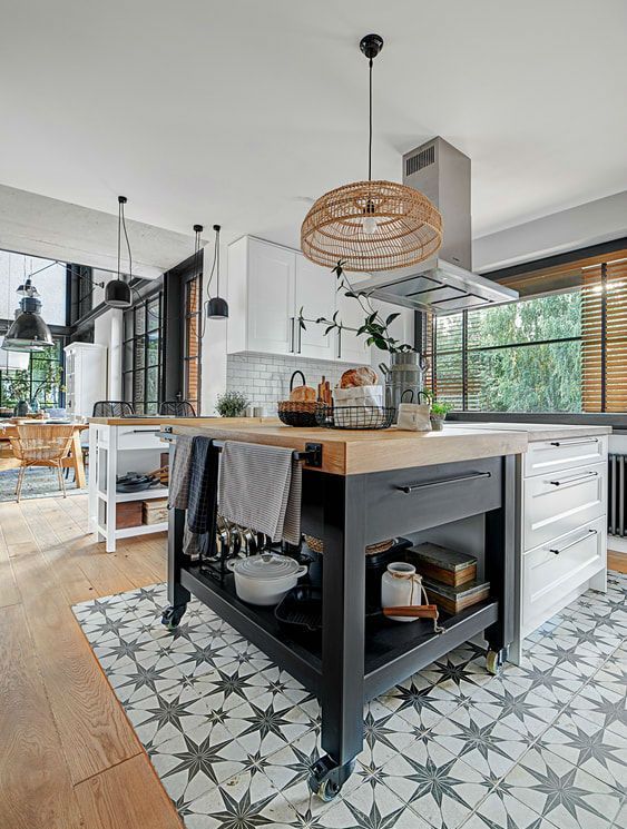 a Scandinavian kitchen with white cabinets, a mobile black kitchen island, a floor transition from laminate to black and white tiles