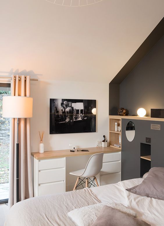 a bedroom with a grey accent wall, a small built-in desk, built-in shelves, a bed with neutral bedding and some decor