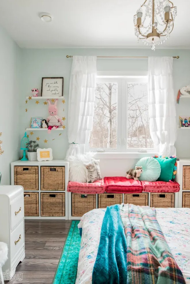 a bright kids' room with a storage bench by the window built of several IKEA Kallax units, with bright decor