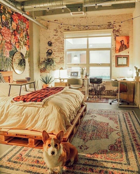 a cathcy bedroom with a large working space at the window, with several chairs, a pallet bed and a small table, a round mirror and some lights