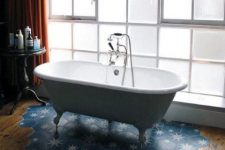 a chic bathroom with a laminate to blue hex tile floor, a vintage clawfoot tub and a side table