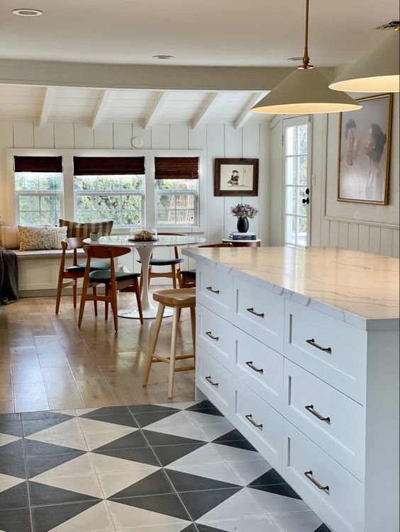 a cottage kitchen with white cabinetry, a checked tilefloor flowing into laminate and a dining zone by the window