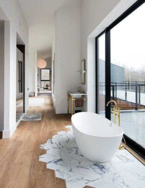 a floor transition from hex tiles to laminate and a bathtub placed next to the window for a lovely view are amazing