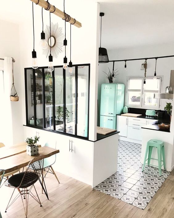 a lovely Scandinavian kitchen with white cabinets, black countertops, a printed tile floor that transitions into laminate, a dining zone