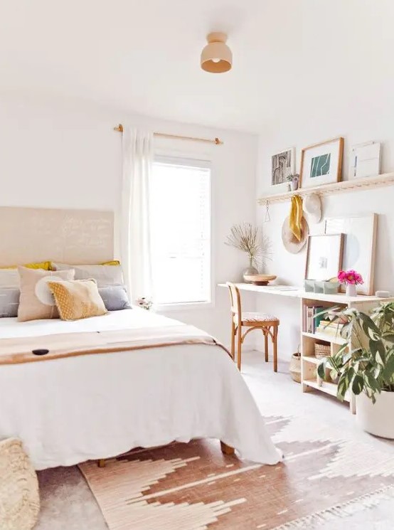 a modern boho bedroom in warm neutrals, with stained furniture, printed textiles and a home office nook that may double as a vanity space