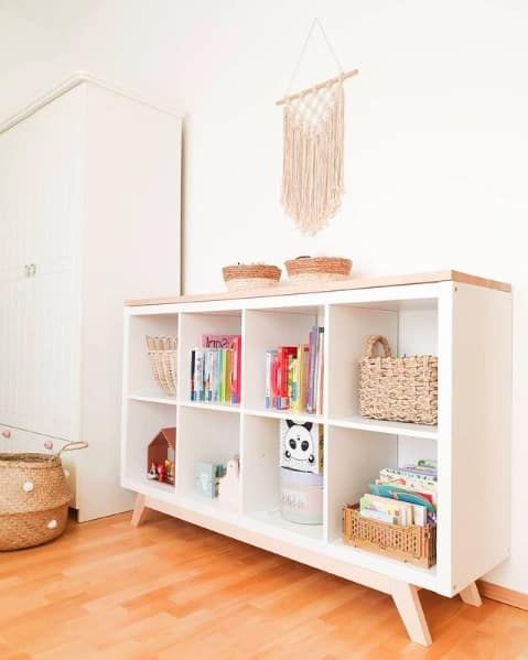 a simple and cool storage unit for a kids' room made of an IKEA Kallax piece with a wooden countertop and wooden legs