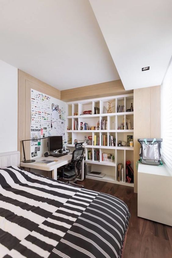a small yet functional bedroom with built-in shelves and a desk, a large bed with printed bedding is amazing
