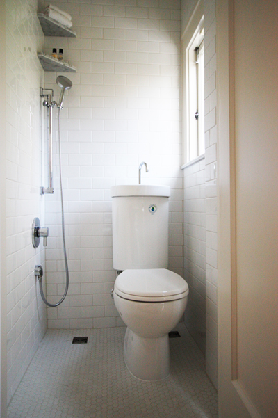 a tiny first floor bathroom that features a compact toilet/sink combo and a shower