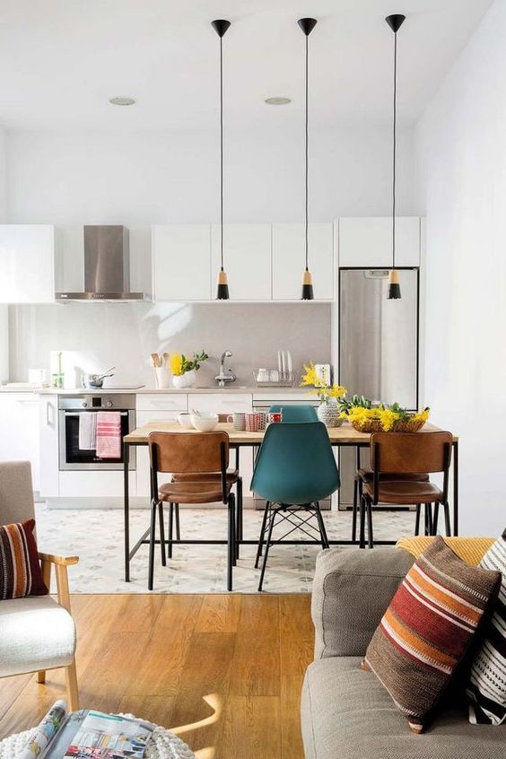 a white Scandinavian kitchen with stainless steel appliances, a dining zone, a tiled floor and a laminate floor in the living room zone