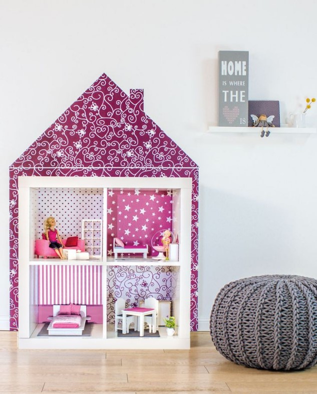 an IKEA Expedit piece turned into a doll house, with fuchsia printed wallpaper, some dolls and toys