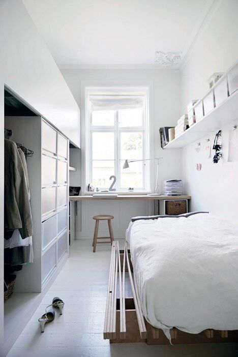 an airy Scandinavian bedroom with a windowsill desk and a stool, a wardrobe, a low bed and a shelf with cubbies