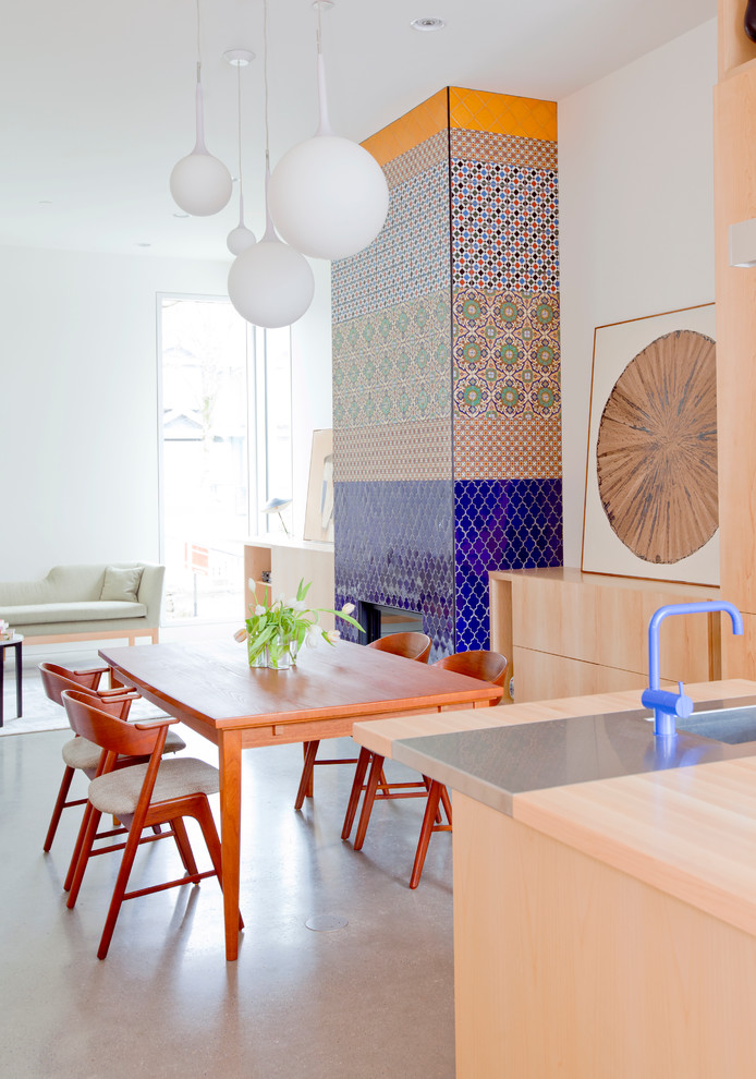 light grey concrete flooring looks great with colorful tiles covering a mantel in this dining room (Novell Design Build)