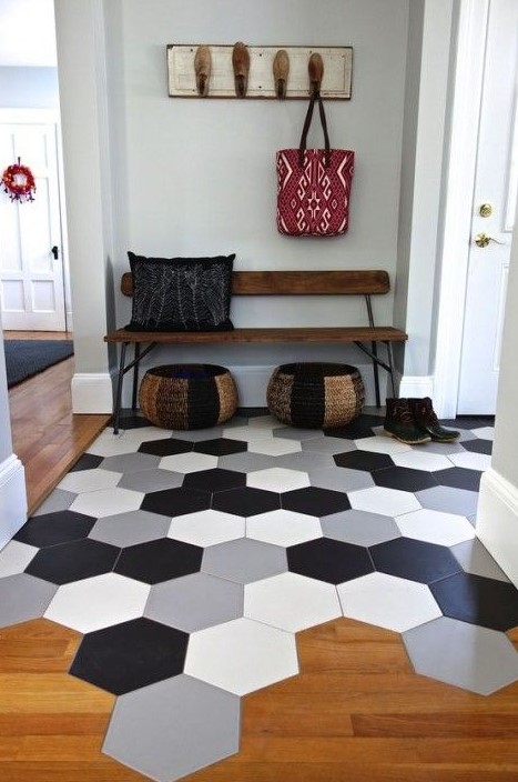 large scale hexagon tiles in different colors in the entryway flow into warm-colored laminate in the rest of the space