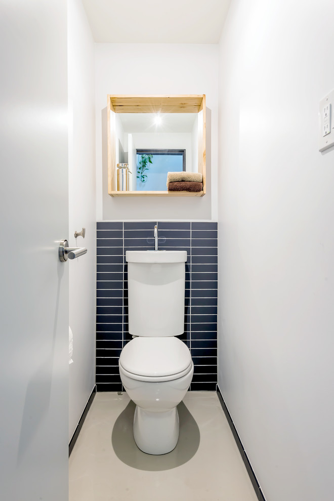 A tiny toilet room that features everything necessary including a mirror.