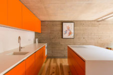 02 The kitchen is designed in bold orange, the space is minimal and uncluttered, everything is hidden