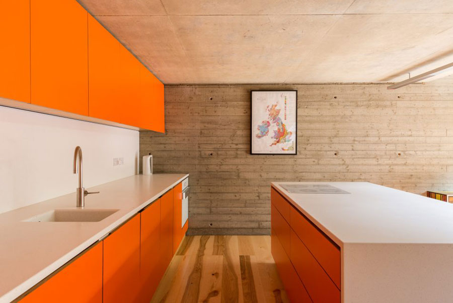 The kitchen is designed in bold orange, the space is minimal and uncluttered, everything is hidden