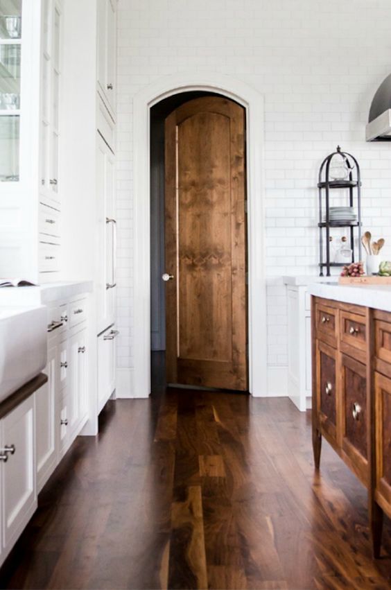 white kitchen with a stained hardwood floor and wood island and door