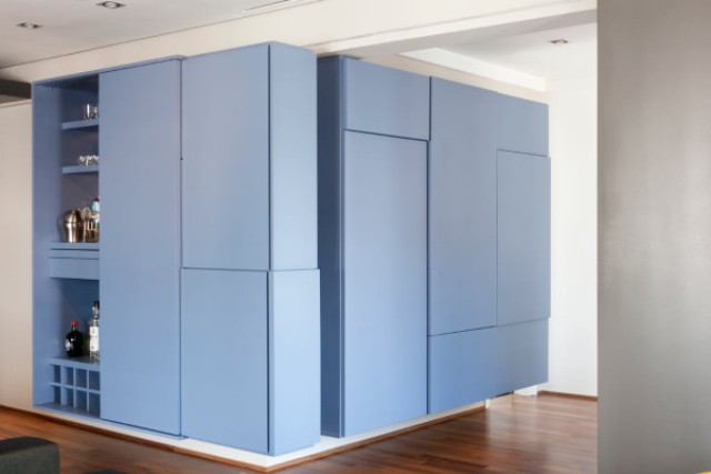 A blue box was built between the open living space and the bedroom to house storage and a home bar with a mixing station