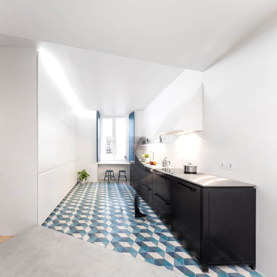 The kitchen is modern and minimalist, with 3D floor tiles and black metal cabinets