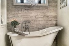 04 faux stone works as a perfect backdrop for a claw foot tub and a refined chandelier