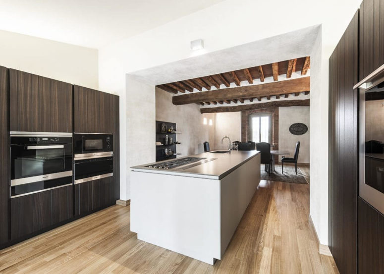 Kitchen cabinets are clad with dark wood, which contrasts with stainless steel appliances