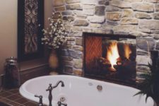 08 rough stone wall with a fireplace makes a bathroom inviting