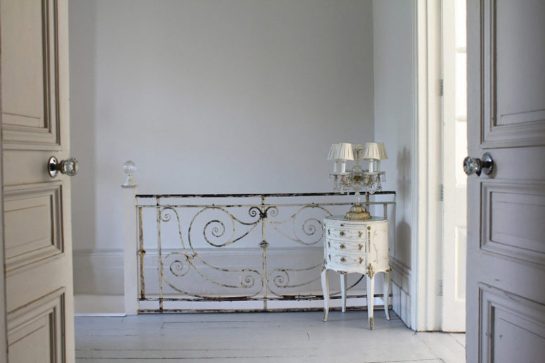 The stairs is decorated in shabby chic way, and the nightstand with an antique lamp highlights it