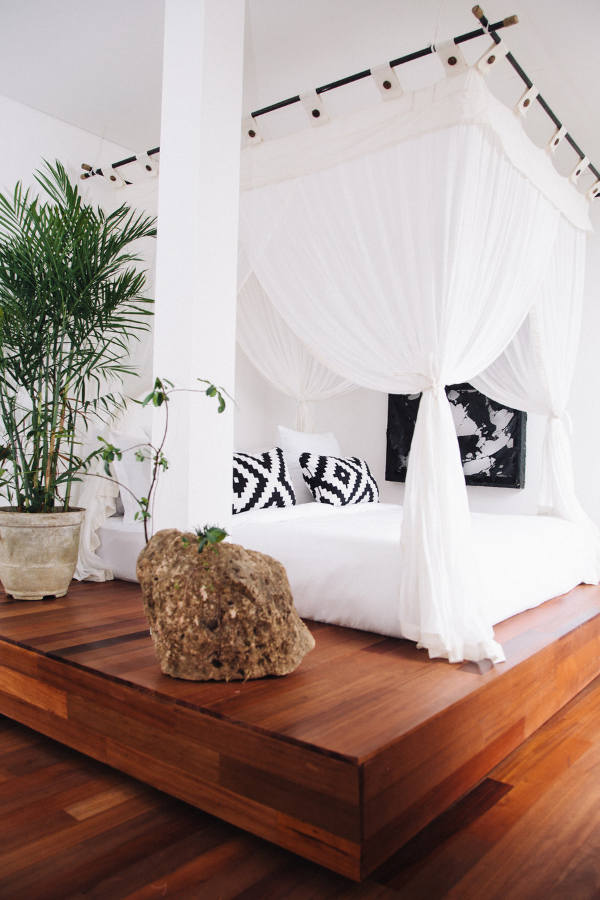 the bed is set on a platform in this room, and the platform is used for a large tree and stone