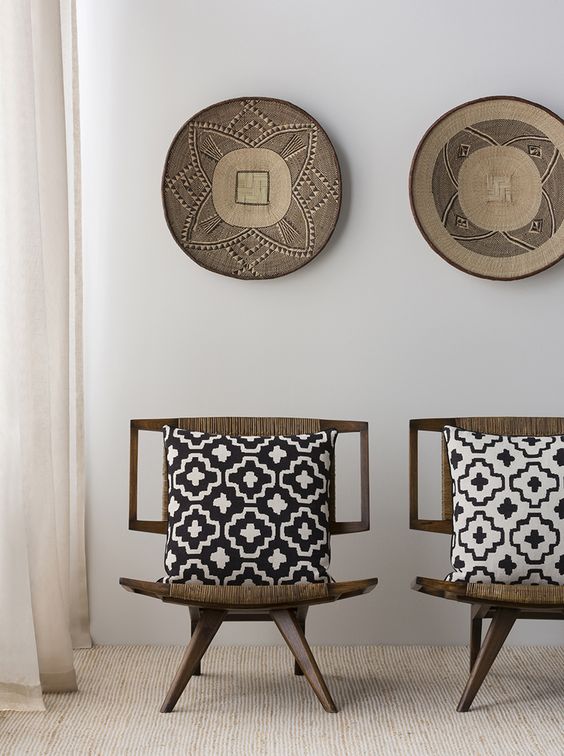 11 Dark wood chairs upholstered with ethnic woven fabrics and matching pottery on the wall