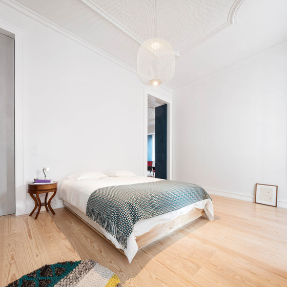 The master bedroom is clean and uncluttered, with colorful textiles and a cool hanging lamp
