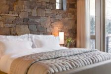 13 natural stone accent wall behind the headboard makes this bedroom cozier and more inviting