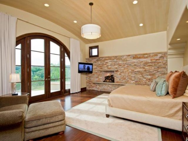 cozy modern bedroom with a fireplace stone wall