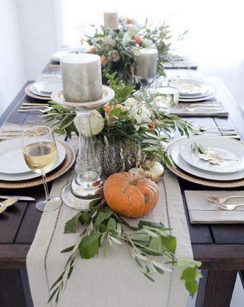 natural pumpkins, greenery and large candles on a fabric table runner