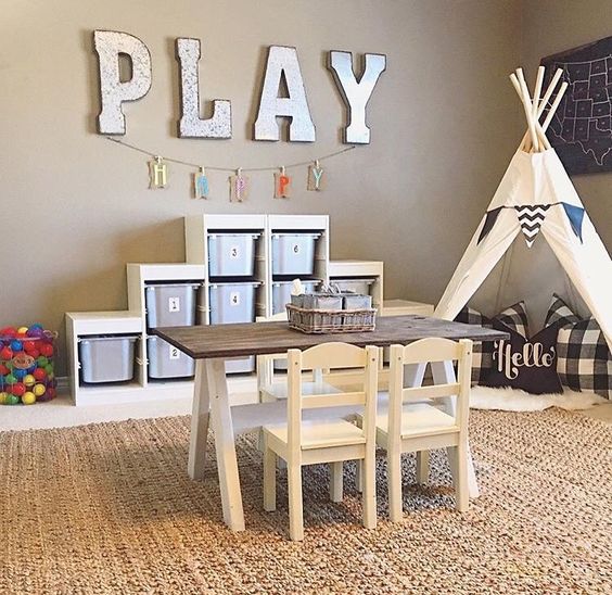 play area with a teepee, a table for drawing and a shelving unit with cubbies