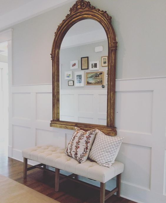 refined entryway with a mirror over wood panelling