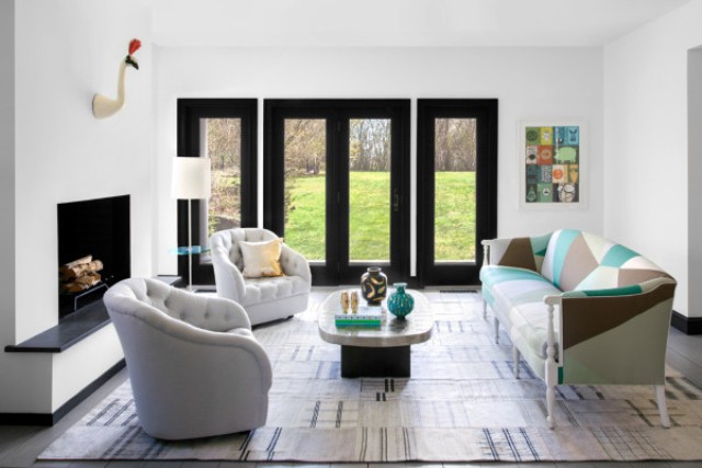 The living room shows a non working built in fireplace, a couple of chairs and an awesome geometric colorful sofa The living room shows a non-working built-in fireplace, a couple of chairs and an awesome geometric colorful sofa