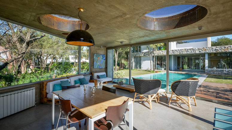 a lounge area with a dining table merges with the pool zone due to the glass doors