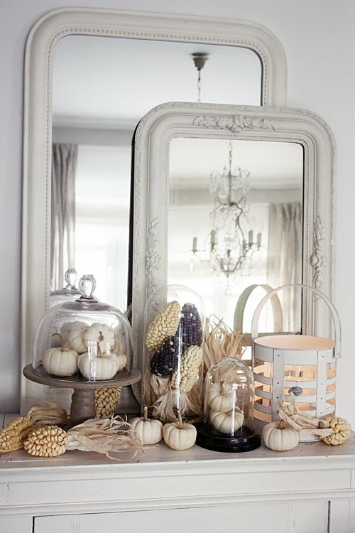 mantel with white pumpkins, vintage framed mirrors and corn in cloches