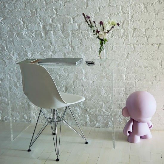 rough white brick stands out as a textural feature, and an acrylic desk doesn't distract attention from the wall