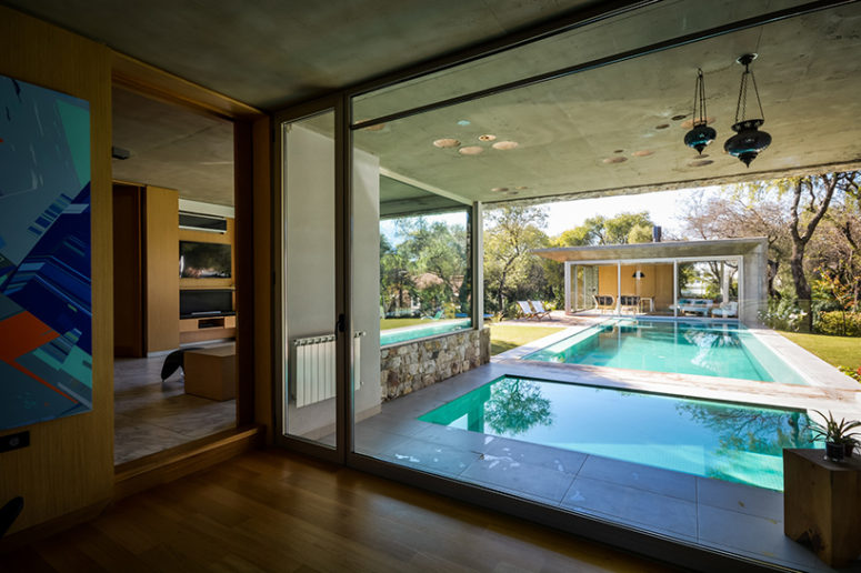 a pool is positioned between the two structures, bordered by wooden decking