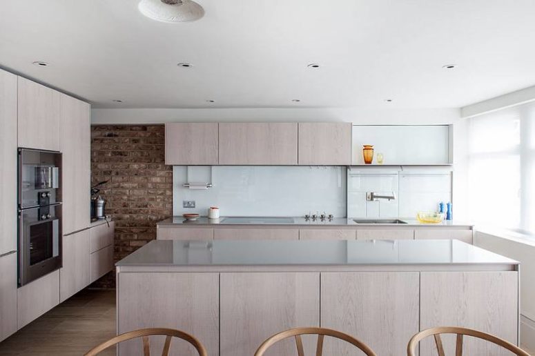 Blush veneer cabinets contrasts with a brick wall, the glass backsplash gives a modern look to the kitchen Blush veneer cabinets contrasts with a brick wall, the glass backsplash gives a modern look to the kitchen